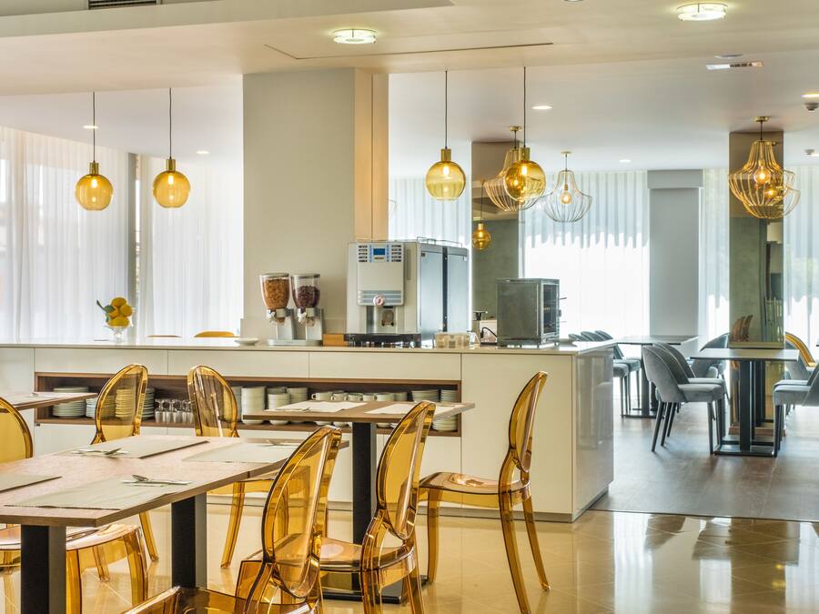 Un comedor moderno con una isla central, sillas de vidrio transparente e iluminación colgante.