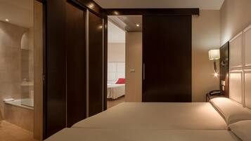 Een moderne hotelkamer met een groot bed, een aparte badkamer met een douchecabine van glas, en een nachtkastje.