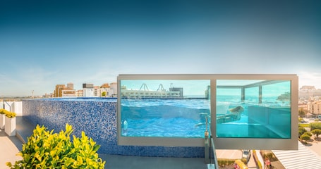 Una piscina techada, una piscina al aire libre, sombrillas