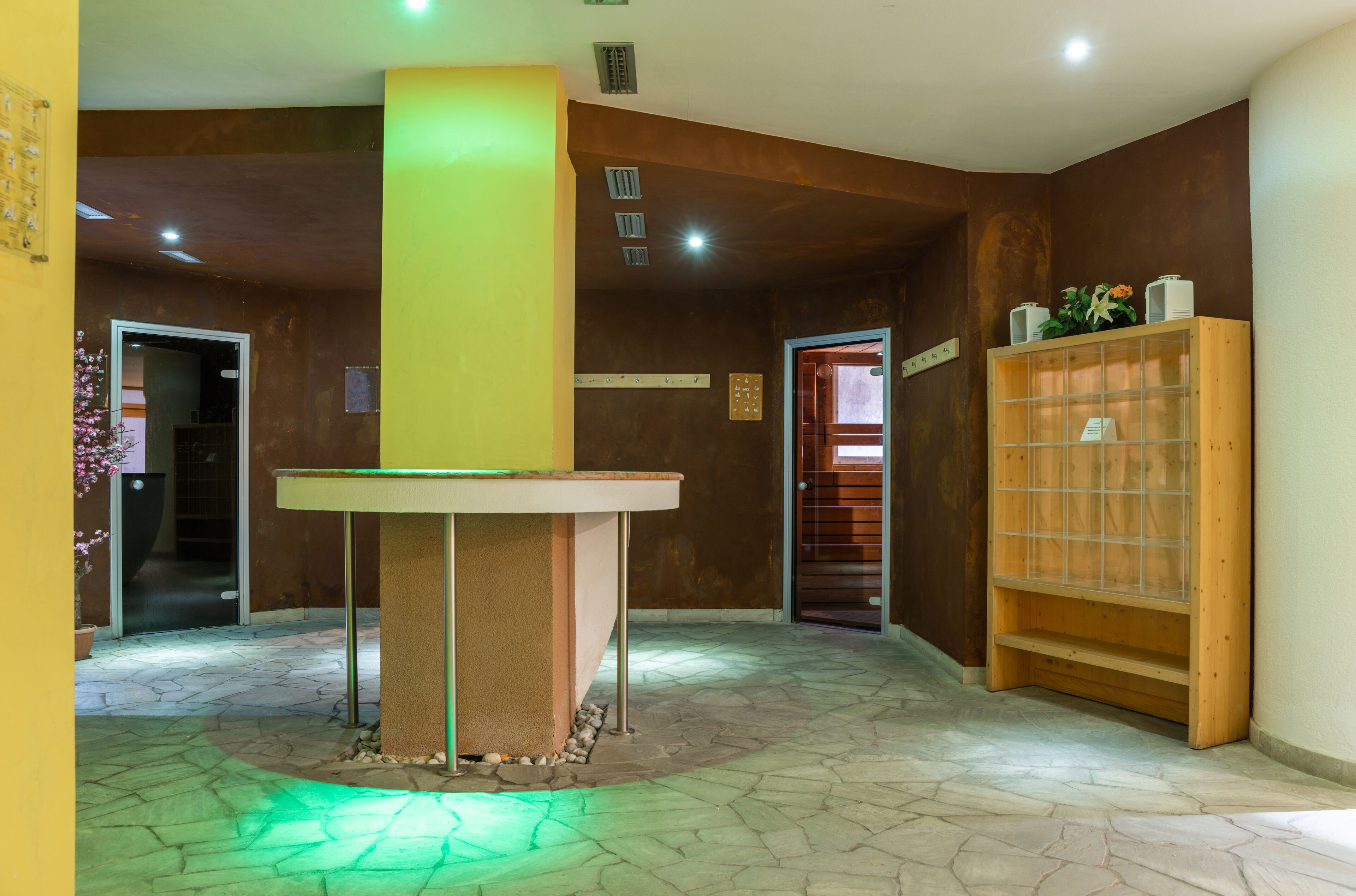 Un vestíbulo con mostrador de recepción, una estantería de madera y suelo de baldosas de piedra.