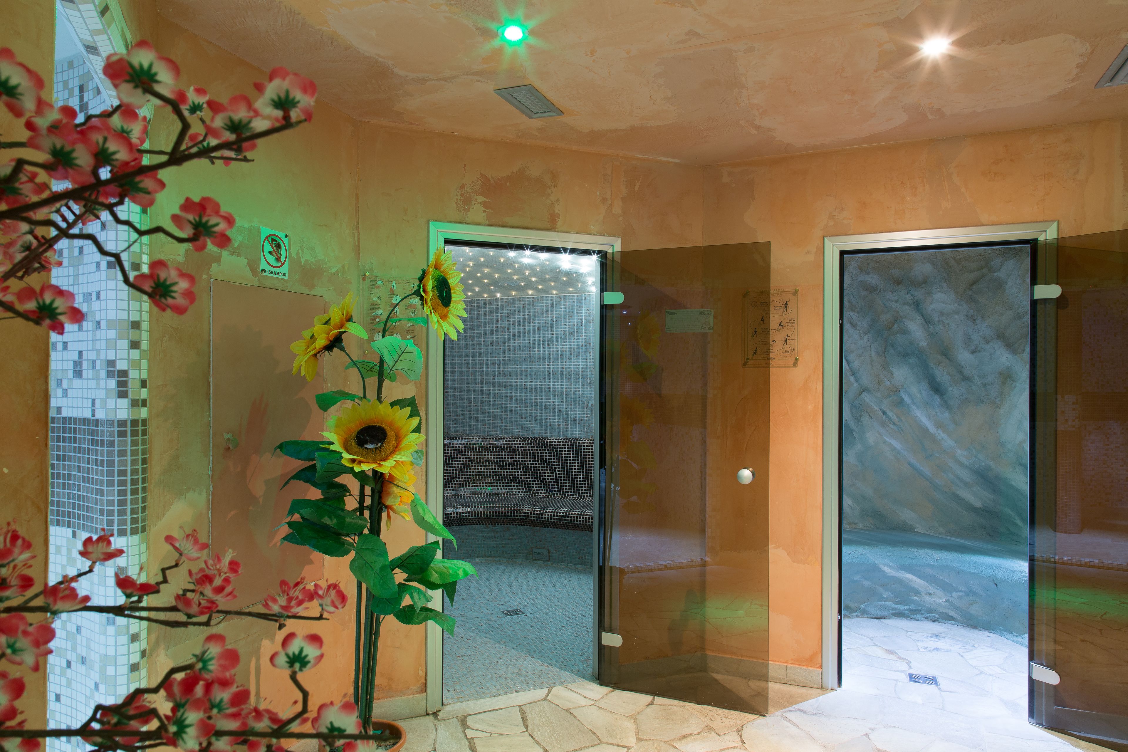 Una habitación con puerta de vidrio, decoración de girasol y suelo de baldosas.