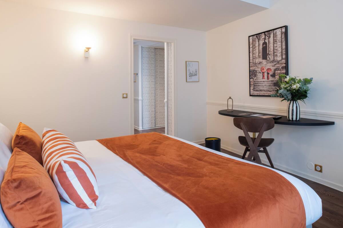 A hotel room with a bed, a desk, and a chair.