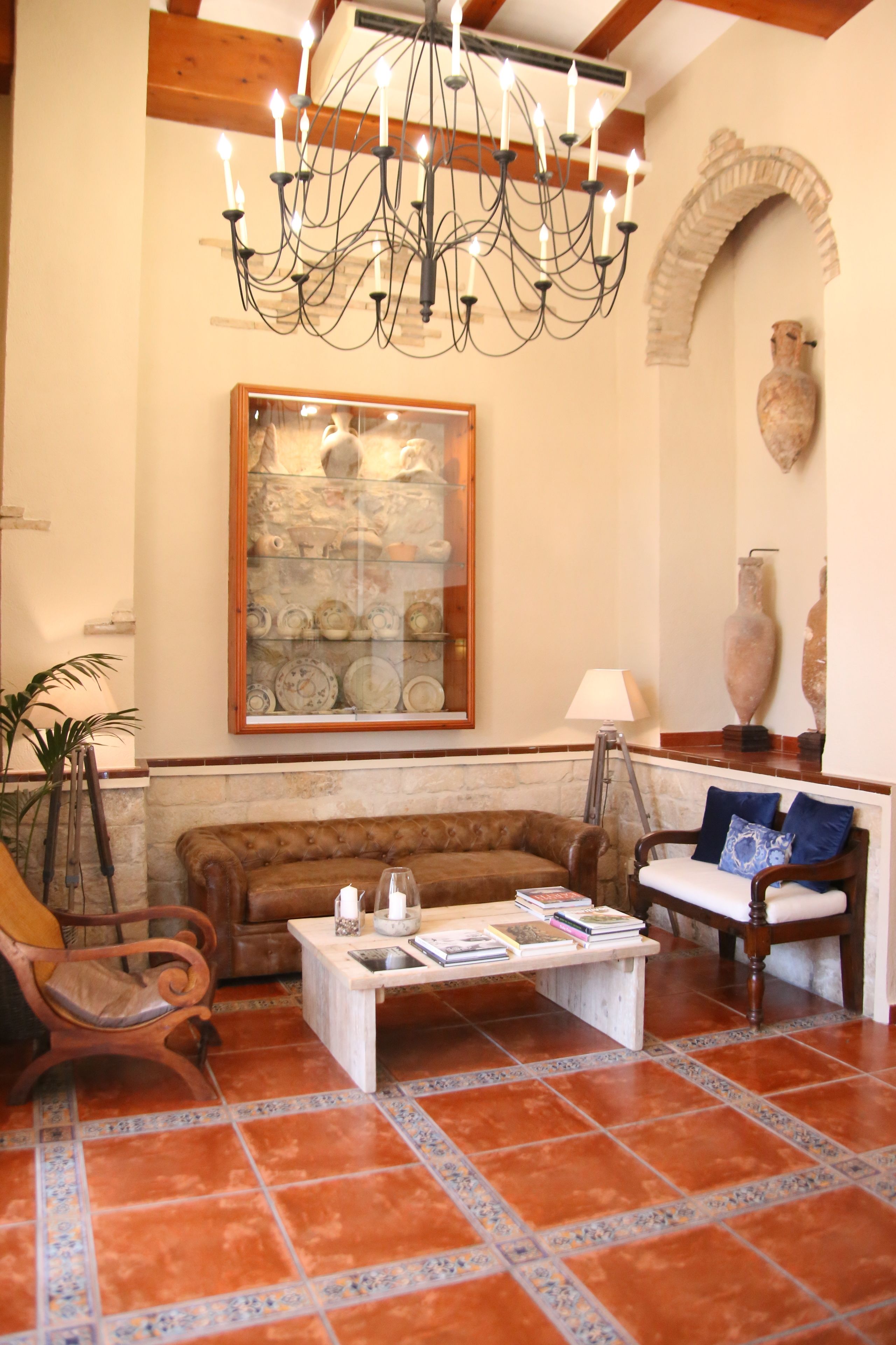 A living room with a brown sofa, a white coffee table, and a chandelier.