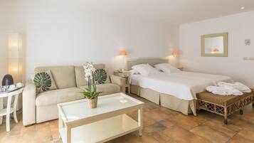 A hotel room with a bed, a sofa, a small table, and a nightstand.