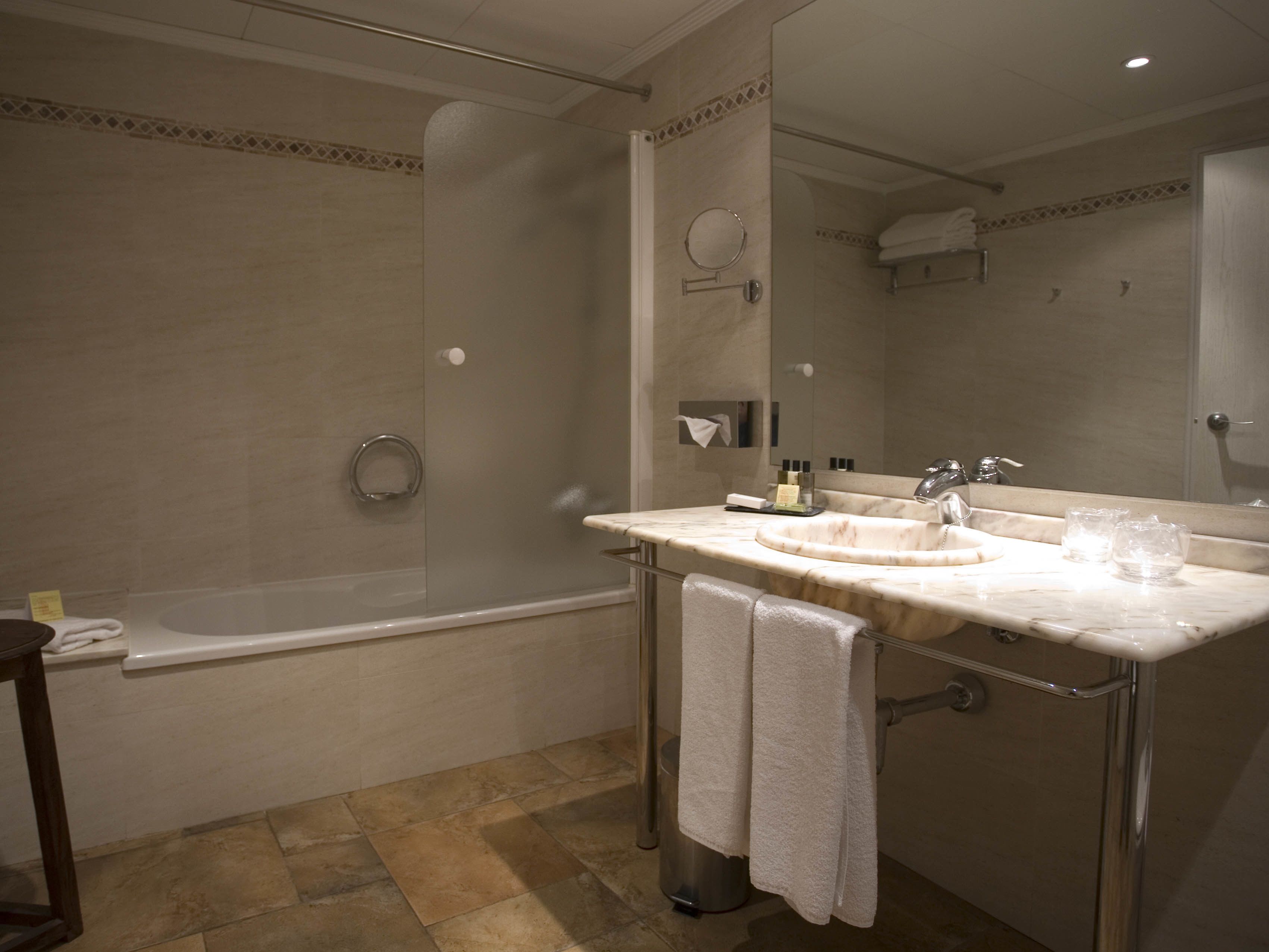 A modern bathroom with a glass-enclosed shower, a marble sink, and a large mirror.