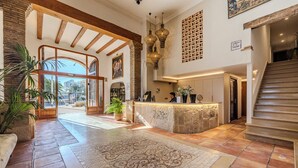A spacious lobby with a reception desk, a staircase, and a large window offering a view of the outside. - La Posada del Mar Hotel (Denia)