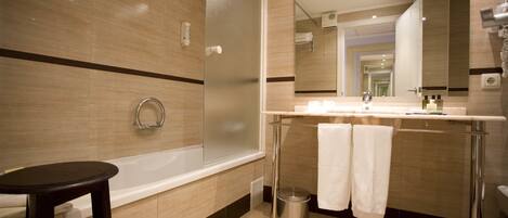 A modern bathroom with a bathtub, a shower, a vanity with a mirror, and a trash can.