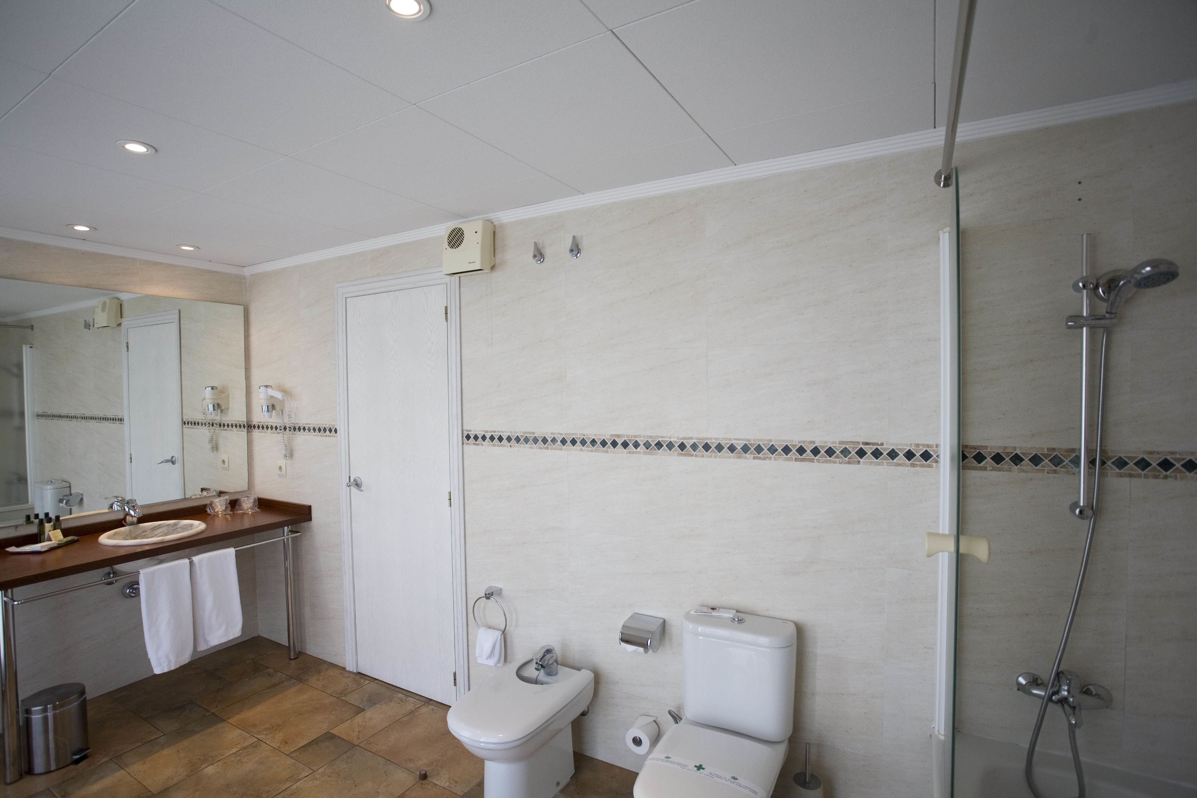 Ein modernes Badezimmer mit großem Spiegel, zwei Waschbecken, Toilette und Dusche.