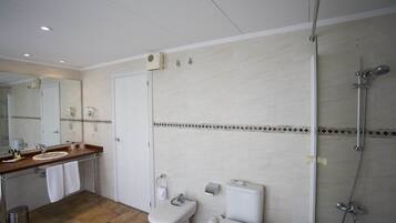 Un baño moderno con un espejo grande, dos lavamanos, un inodoro y una ducha.