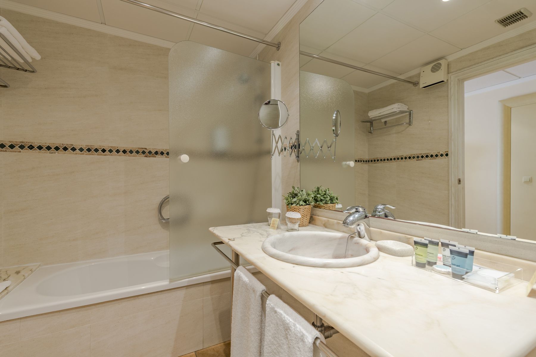 Un baño con bañera, lavabo, espejo y artículos de aseo.