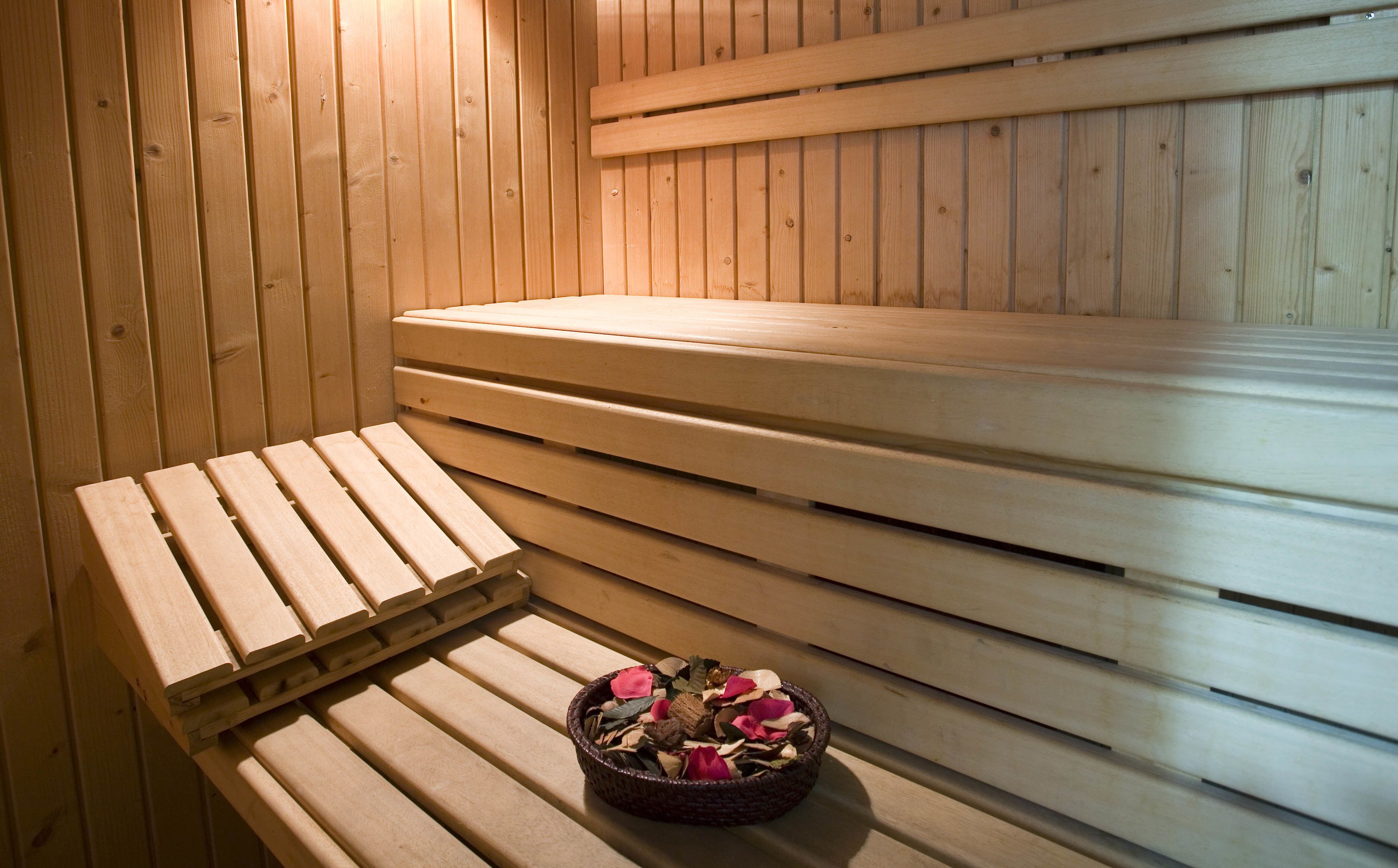 Una sauna amb seients de fusta i una cistella de flors seques.