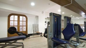 A gym with weightlifting equipment, a bench, and a mirrored wall.