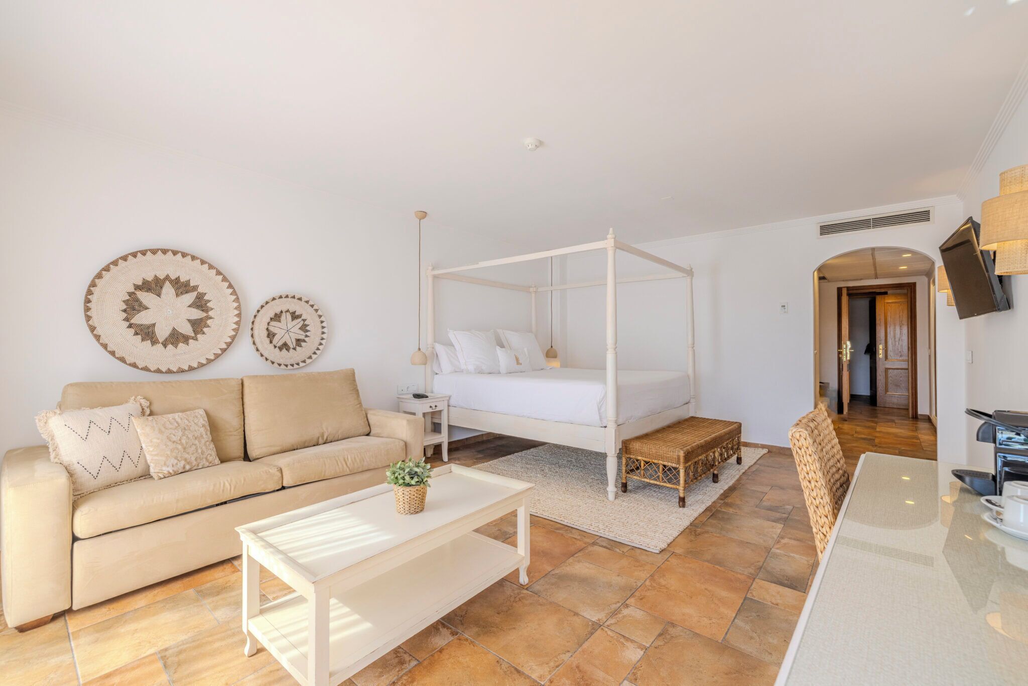 Un dormitorio moderno con una cama con dosel, un sofá, una mesa de centro y un comedor.