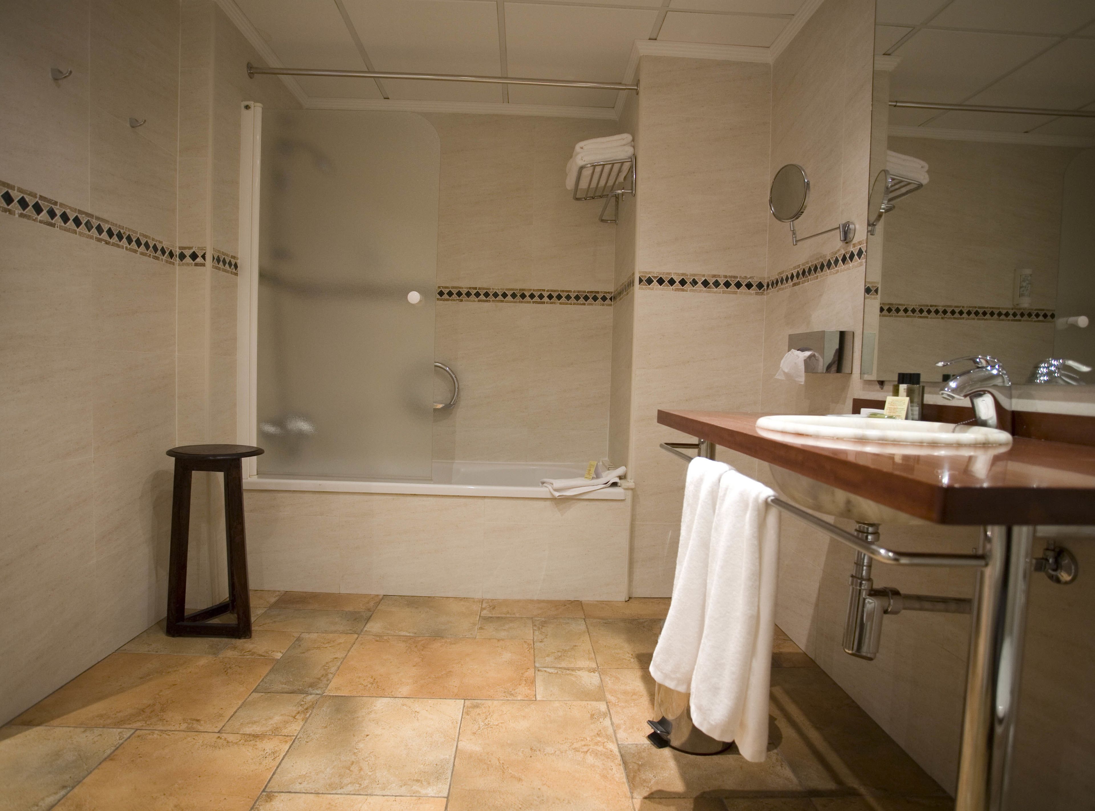 A bathroom with a bathtub, a sink, a mirror, and a towel rack.