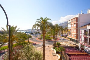 A coastal cityscape with a marina, palm trees, and a building with a sign that reads "CAN BROCHER."