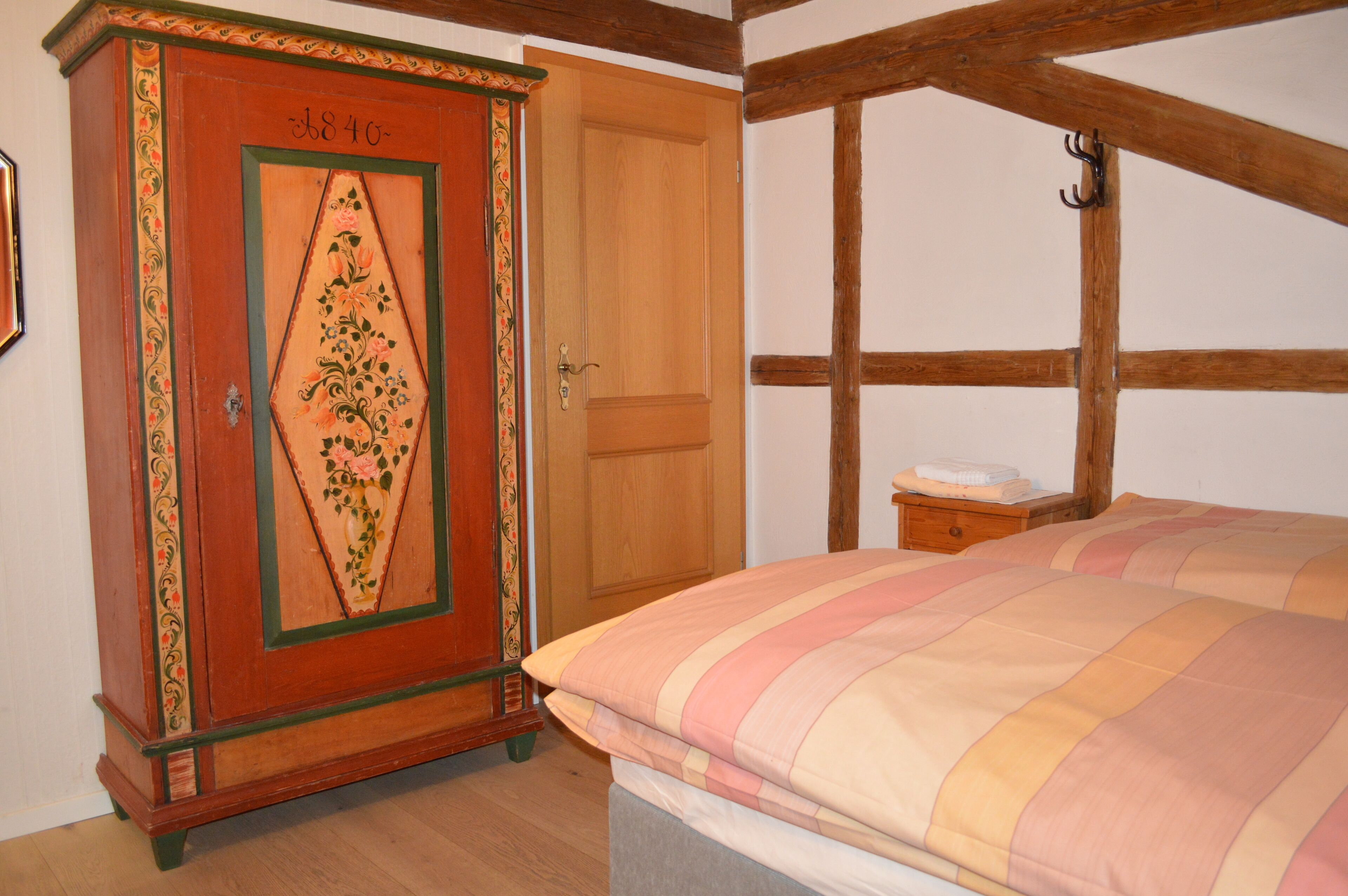 A bedroom with a bed, wooden wardrobe, and a nightstand.