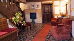 A cozy room with a wooden staircase, a fireplace, and a red carpet. - Landhotel Schwarzes Ross (Steinsfeld)