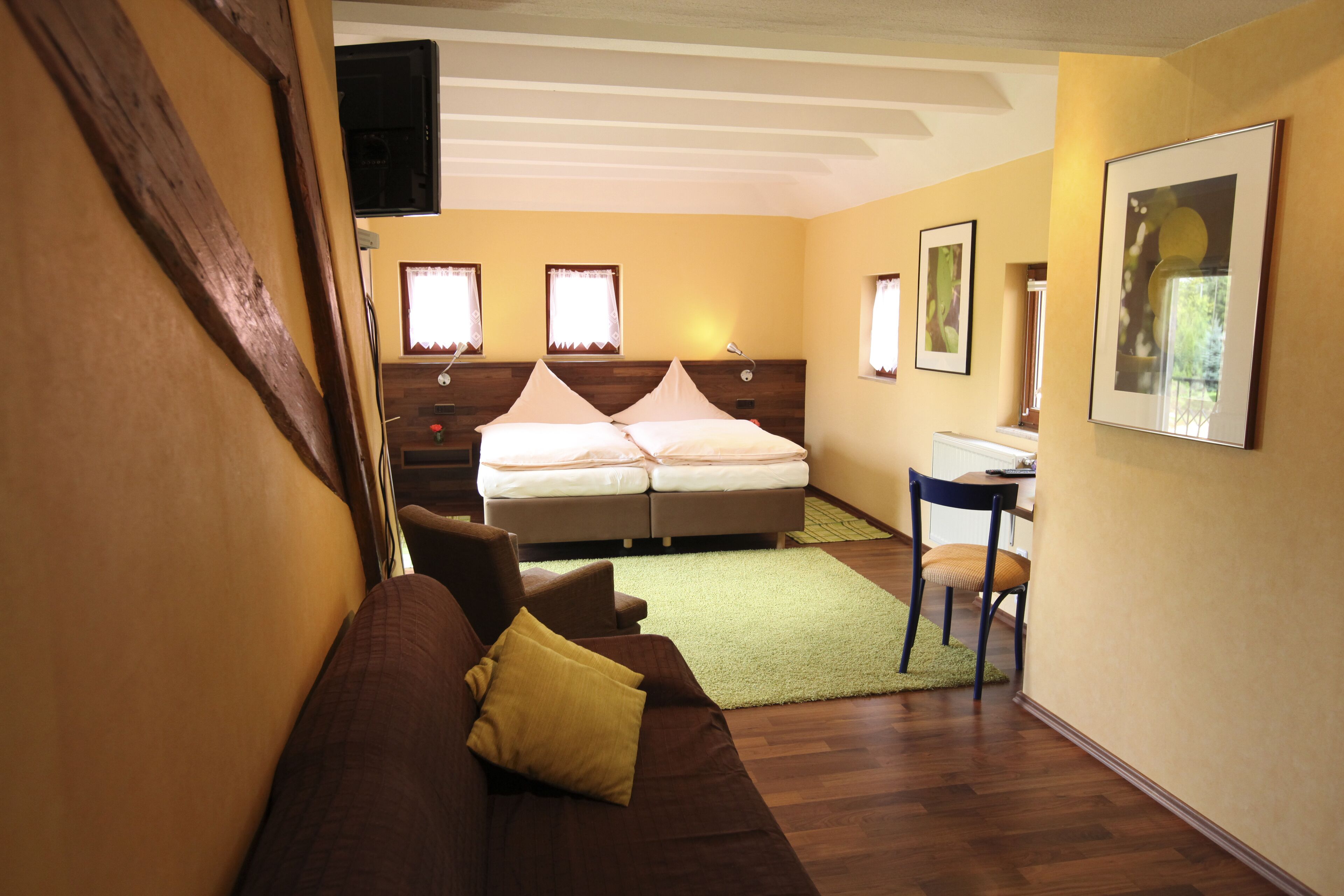 A hotel room with a bed, a desk, a chair, and a couch.