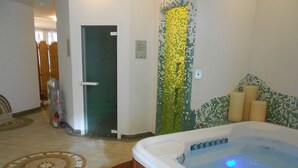 A spa area with a hot tub, a tiled wall, and a door. - Hotel Garni Lago Nembia (San Lorenzo Dorsino)