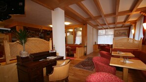 A cozy restaurant with wooden furniture, a bar area, and a seating arrangement. - Hotel Garni Lago Nembia (San Lorenzo Dorsino)