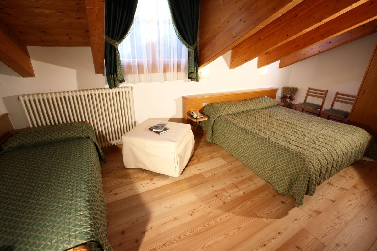 Une chambre avec deux lits, une petite table, une table de chevet, un téléphone et une fenêtre avec des rideaux.