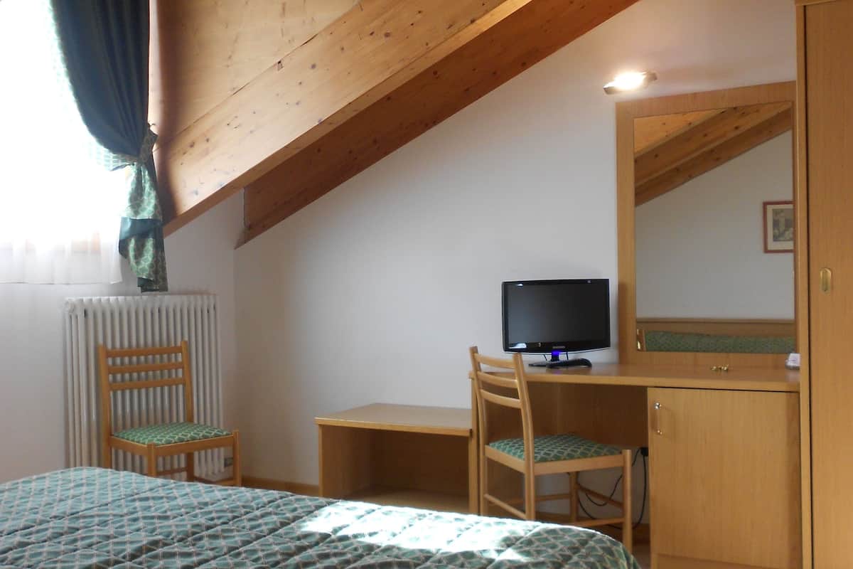 Une chambre à coucher comprenant un lit, un bureau, une chaise, un ordinateur et une armoire.