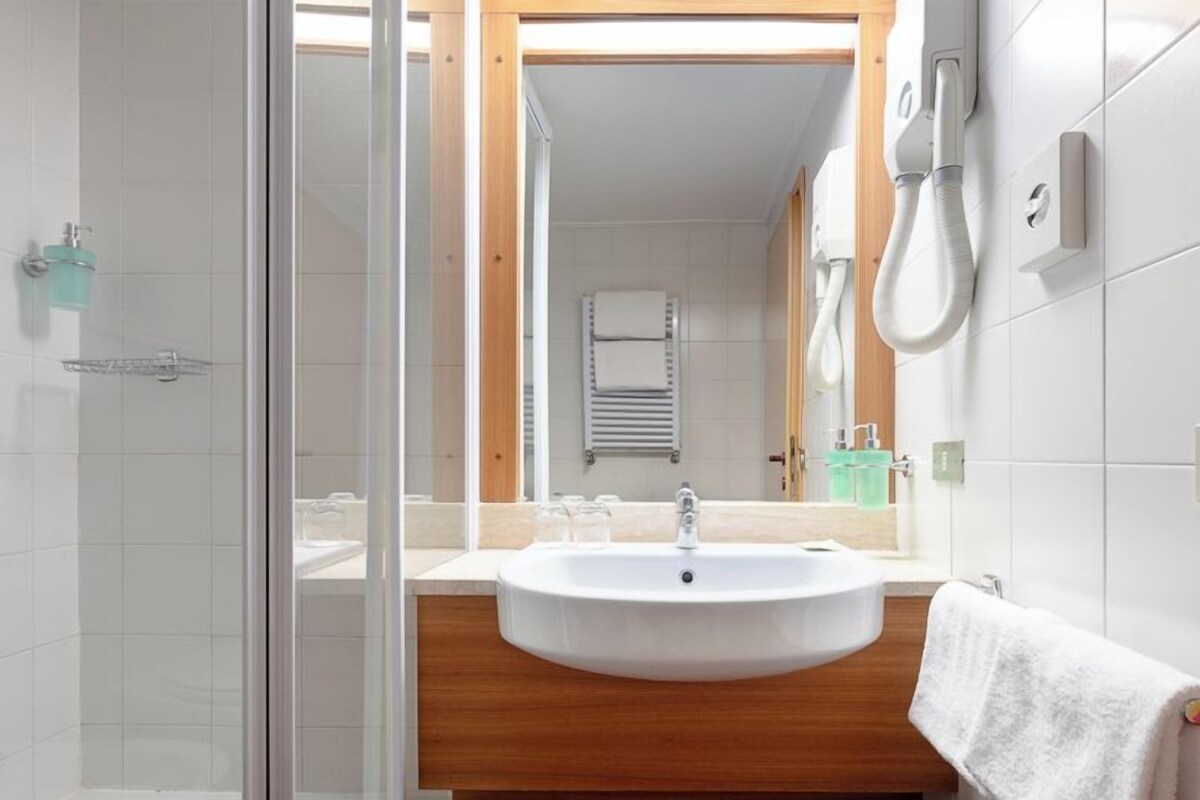 A modern bathroom with a glass shower enclosure, a wooden vanity, a sink, and a towel rack.