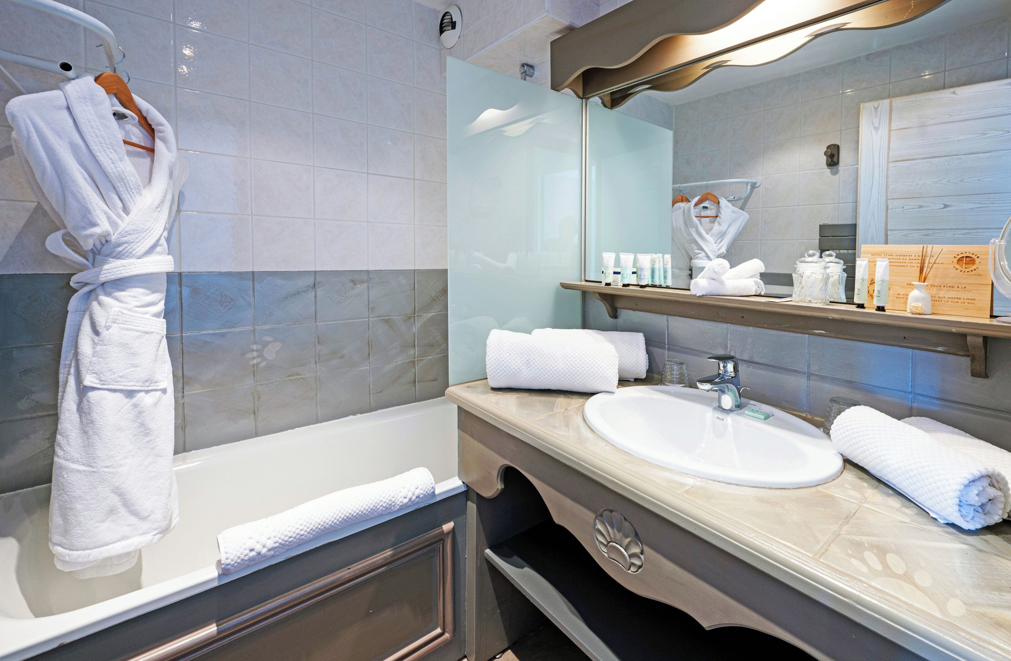 A modern bathroom with a bathtub, a large mirror, and a vanity with a sink and towel rack.
