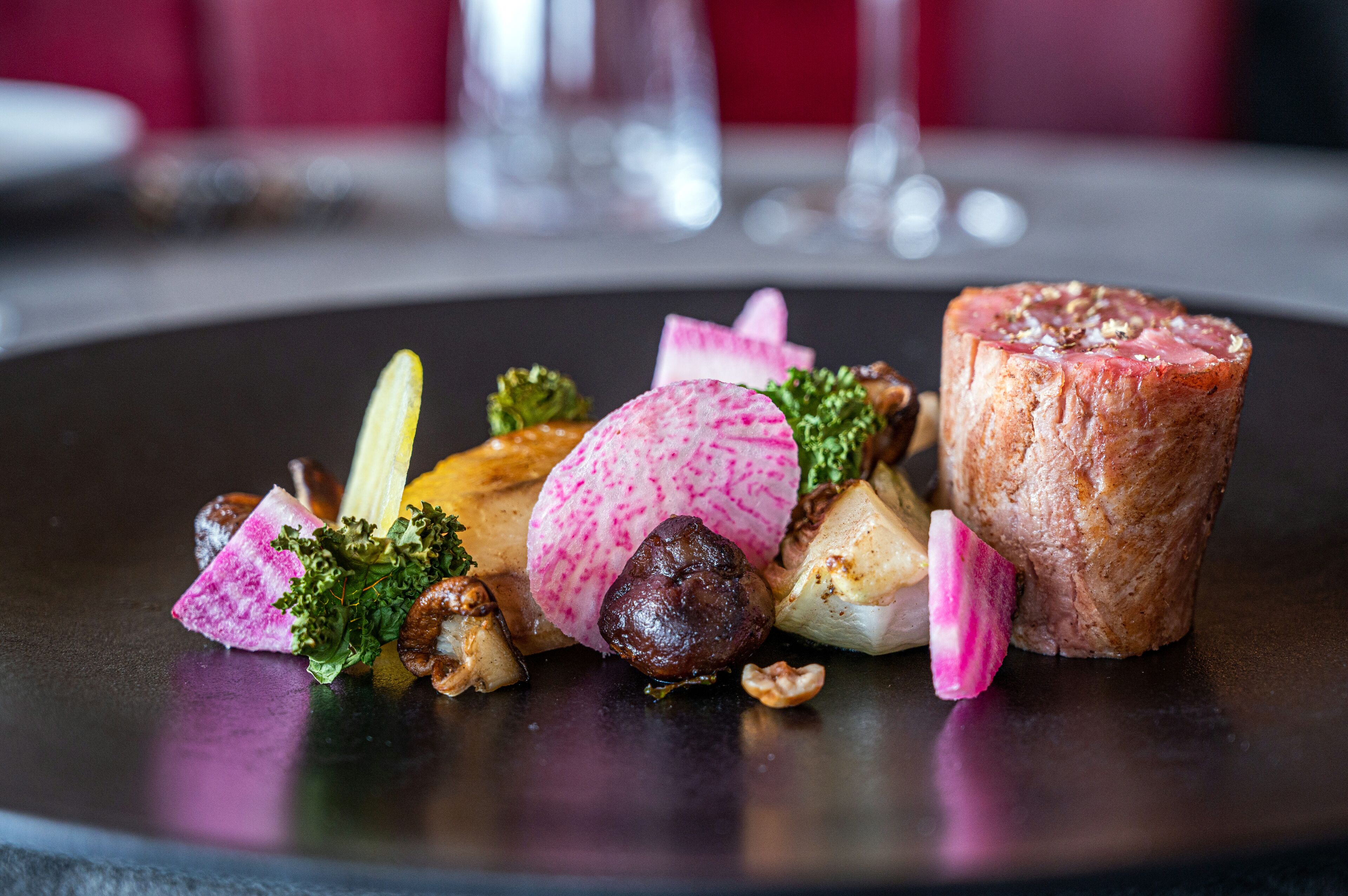 A plate of food with various items including a cylindrical meat, vegetables, and nuts.