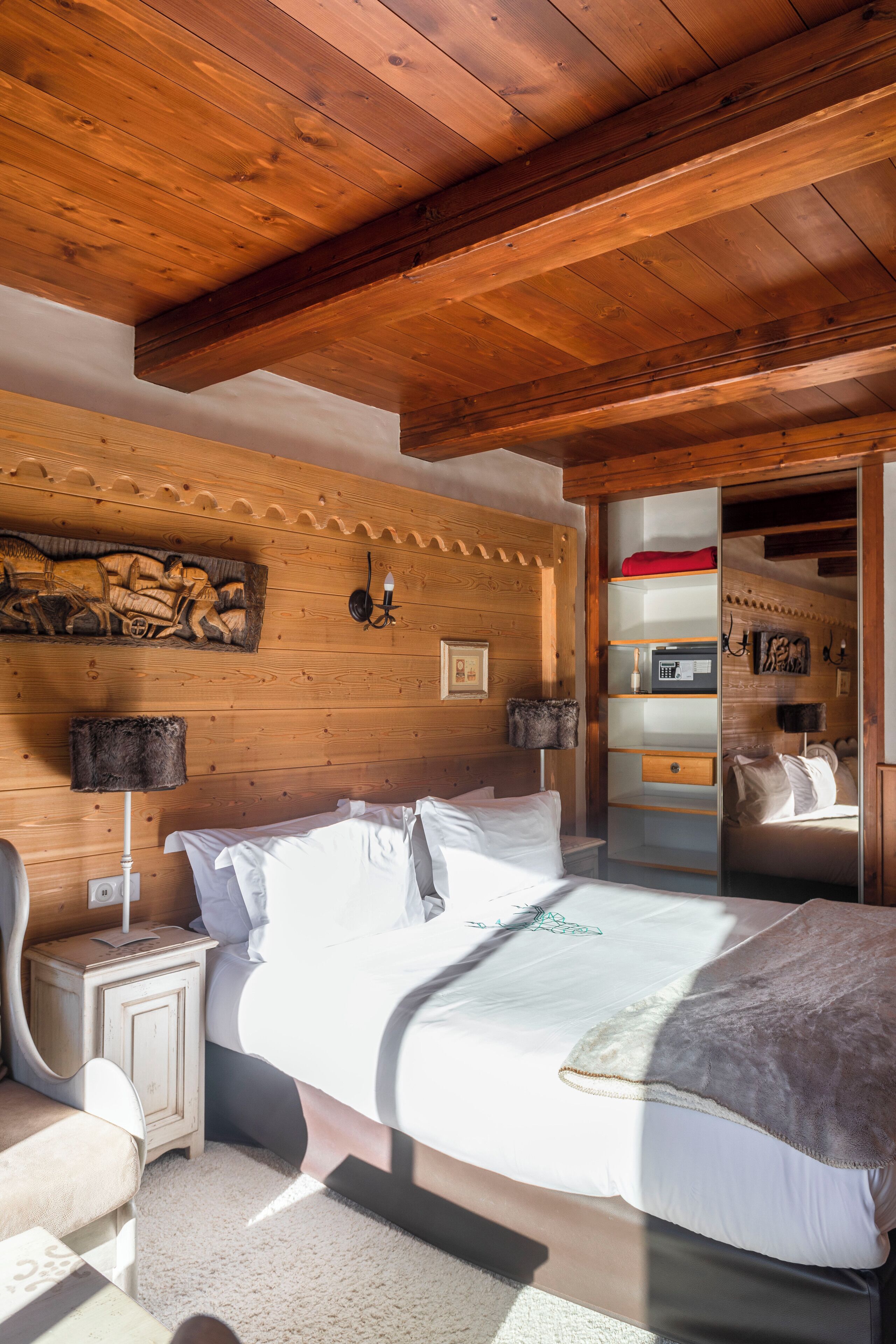 Un dormitorio con paneles de madera, una cama, mesitas de noche y una estantería empotrada.