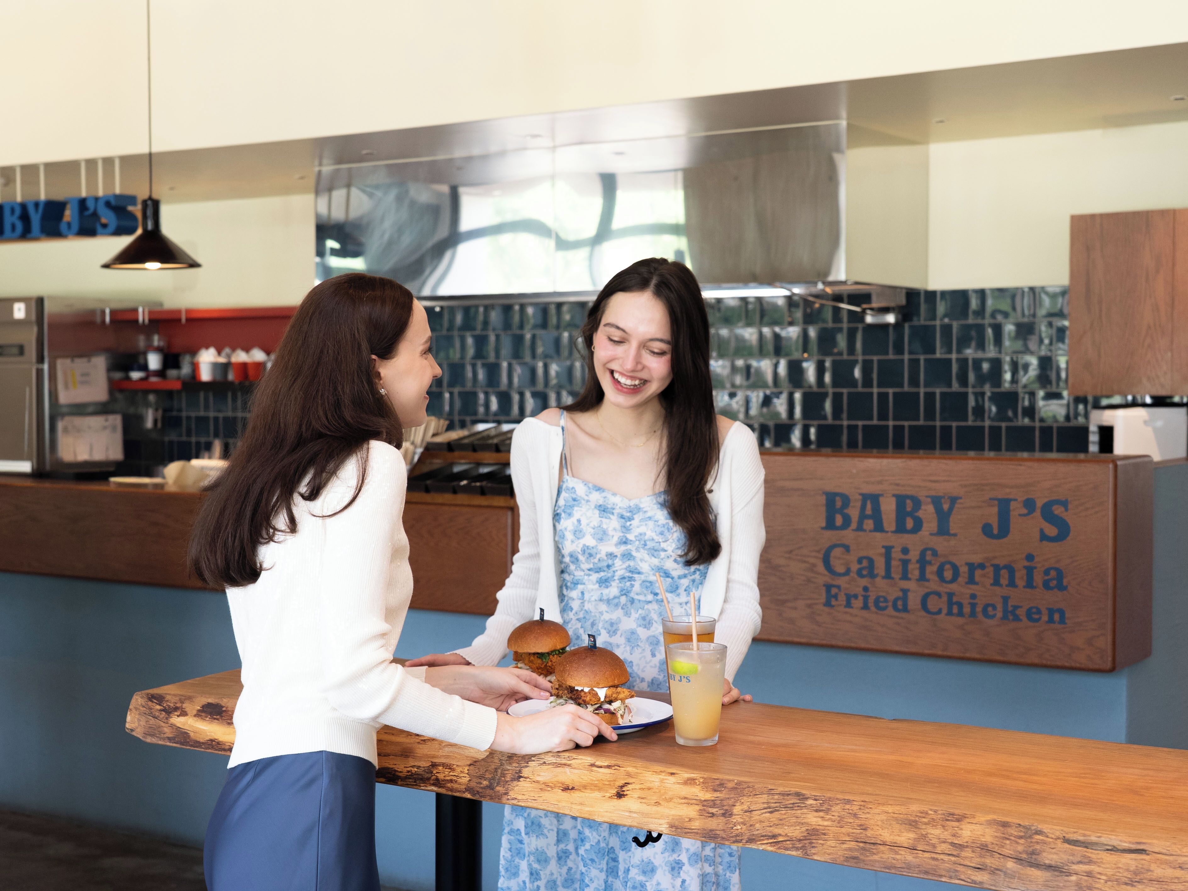 A restaurant counter with a menu board reading "BABY J'S California Fried Chicken".