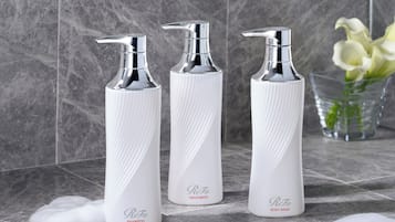 Three white bottles with pump dispensers on a tiled surface.