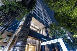 Un moderno edificio de hotel con un letrero llamativo que dice "TOKYU STAY HOTEL".