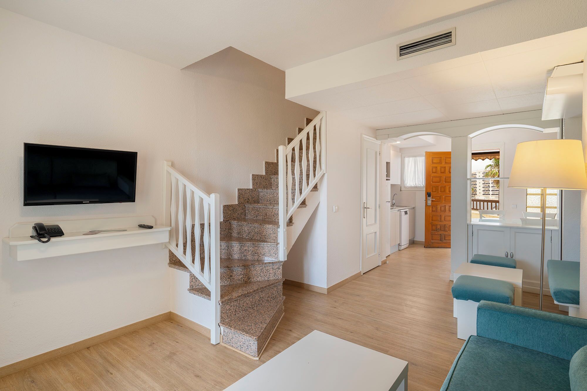 Un salon moderne doté d’un téléviseur à écran plat, d’un escalier, d’un coin cuisine et d’un balcon offrant une vue agréable.