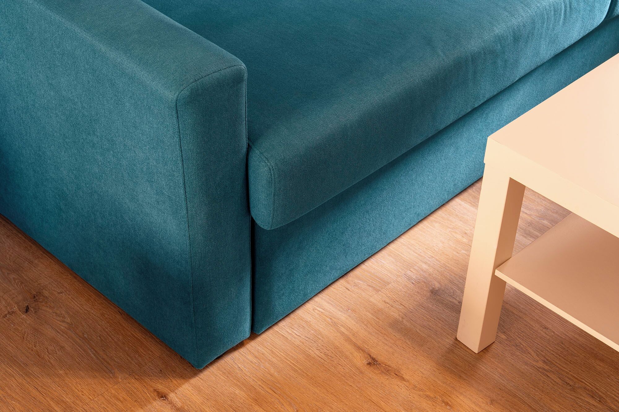 Un sofá color turquesa con una mesita de madera a su lado.