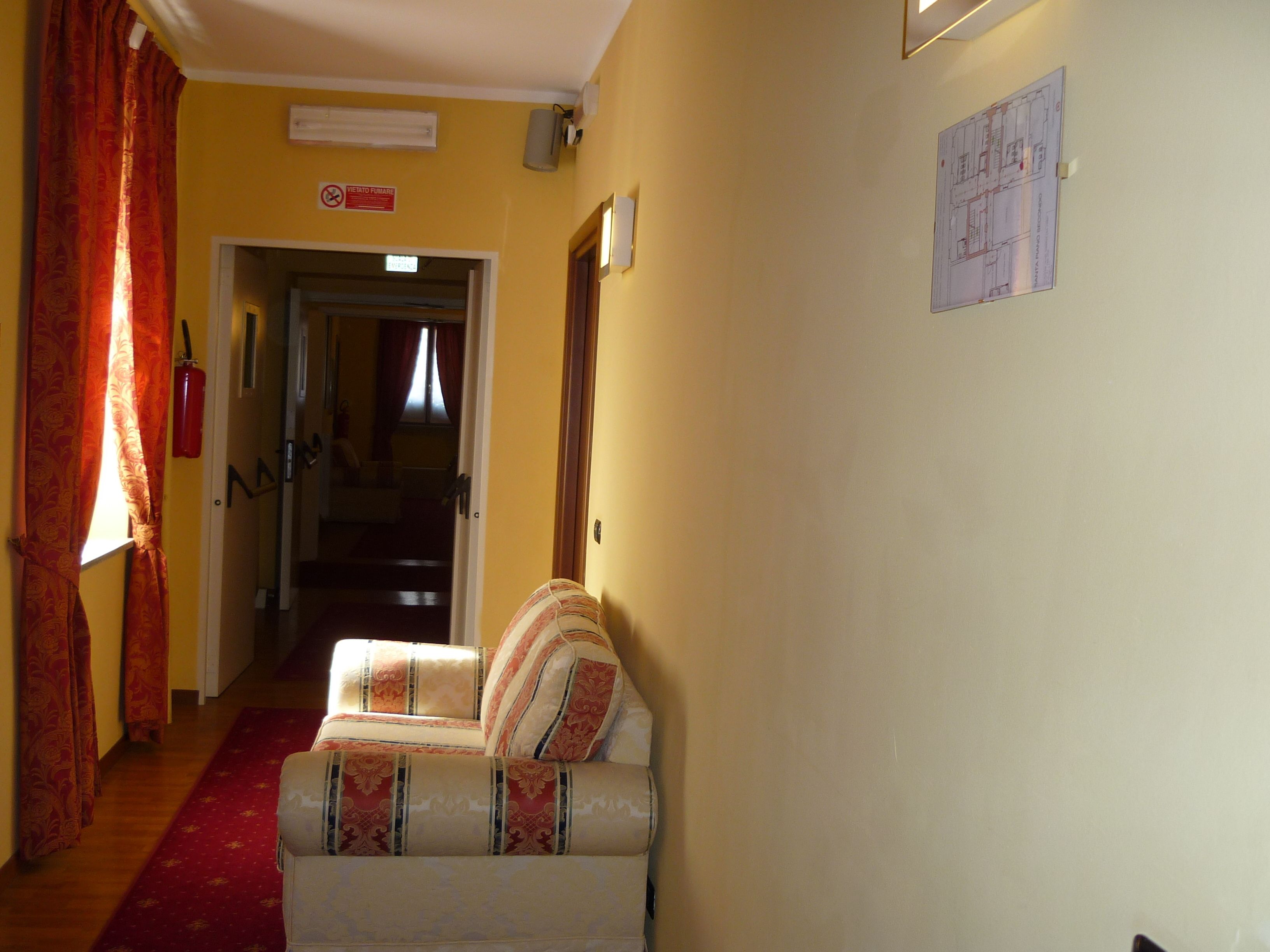 Ein Flur mit einer gemusterten Couch, einem roten Teppich und einer Treppe, die in ein weiteres Zimmer führt.