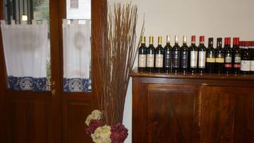 A wooden cabinet with wine bottles and a vase with dried plants.