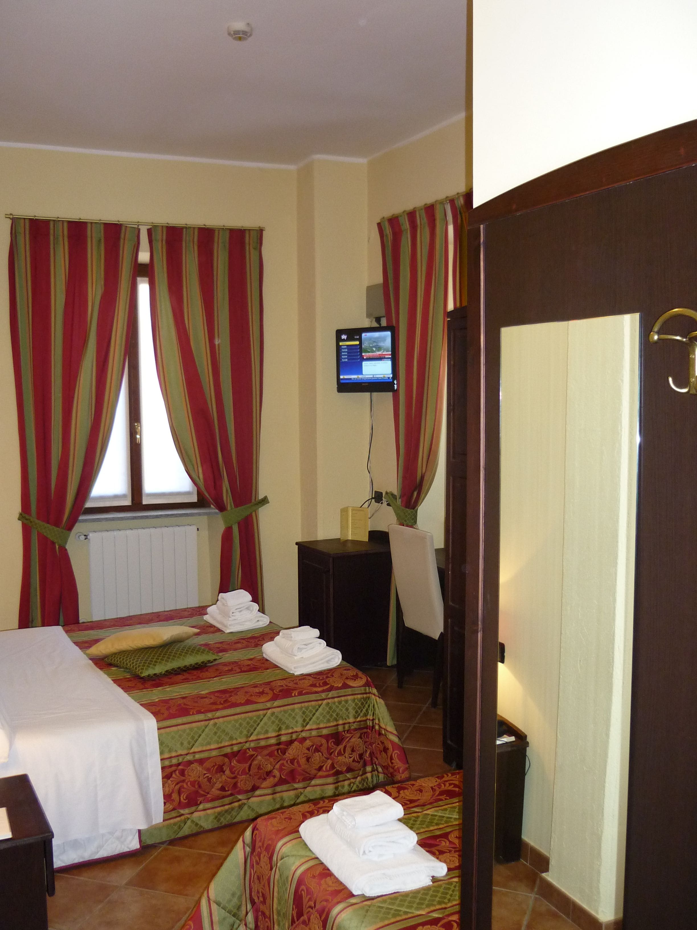 A hotel room with two beds, a TV, a desk, and a chair.