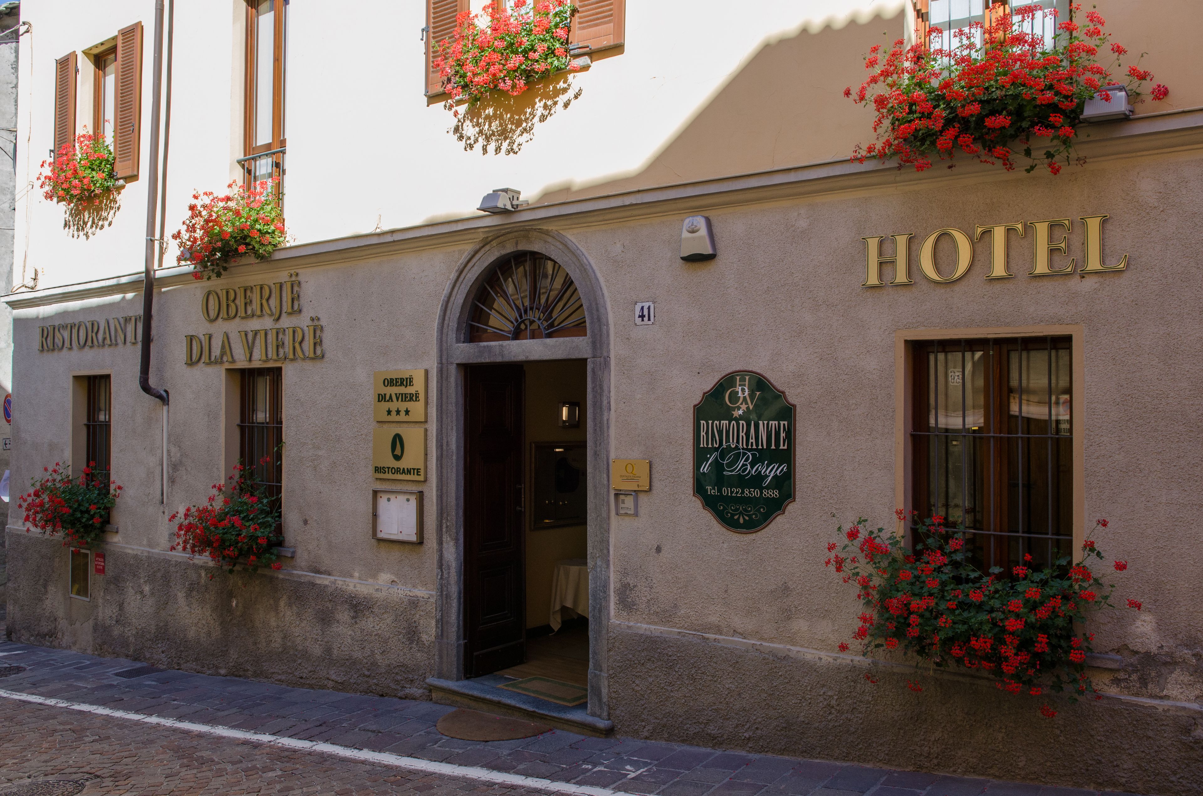 Eine Hotelscheune mit Restaurantschild, einer Klingel und Blumenkästen.