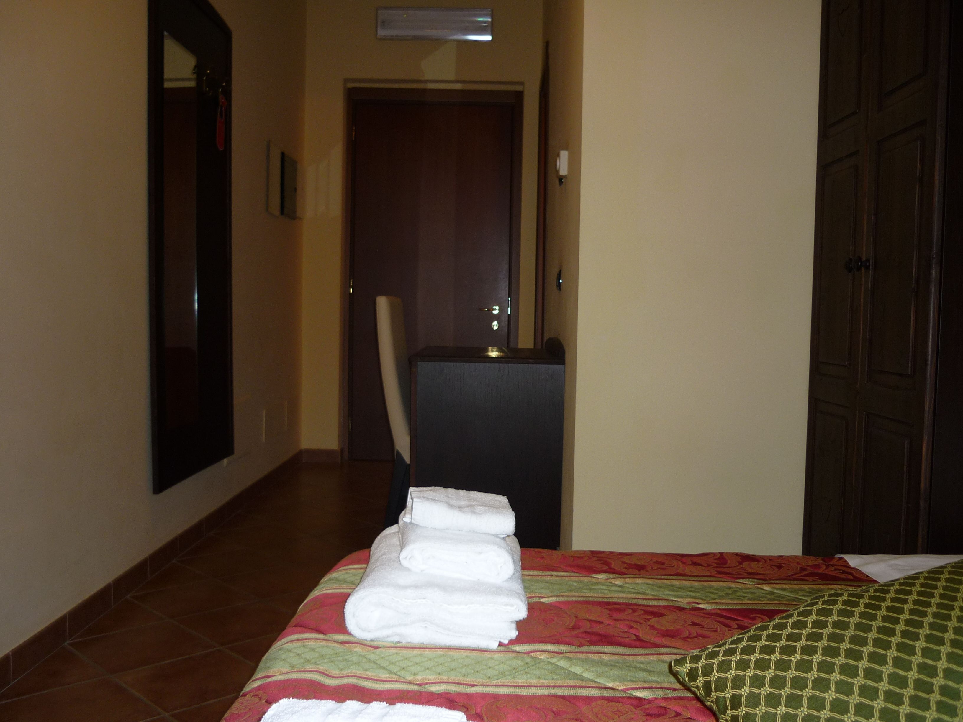 Una habitación de hotel con cama, escritorio y espejo.