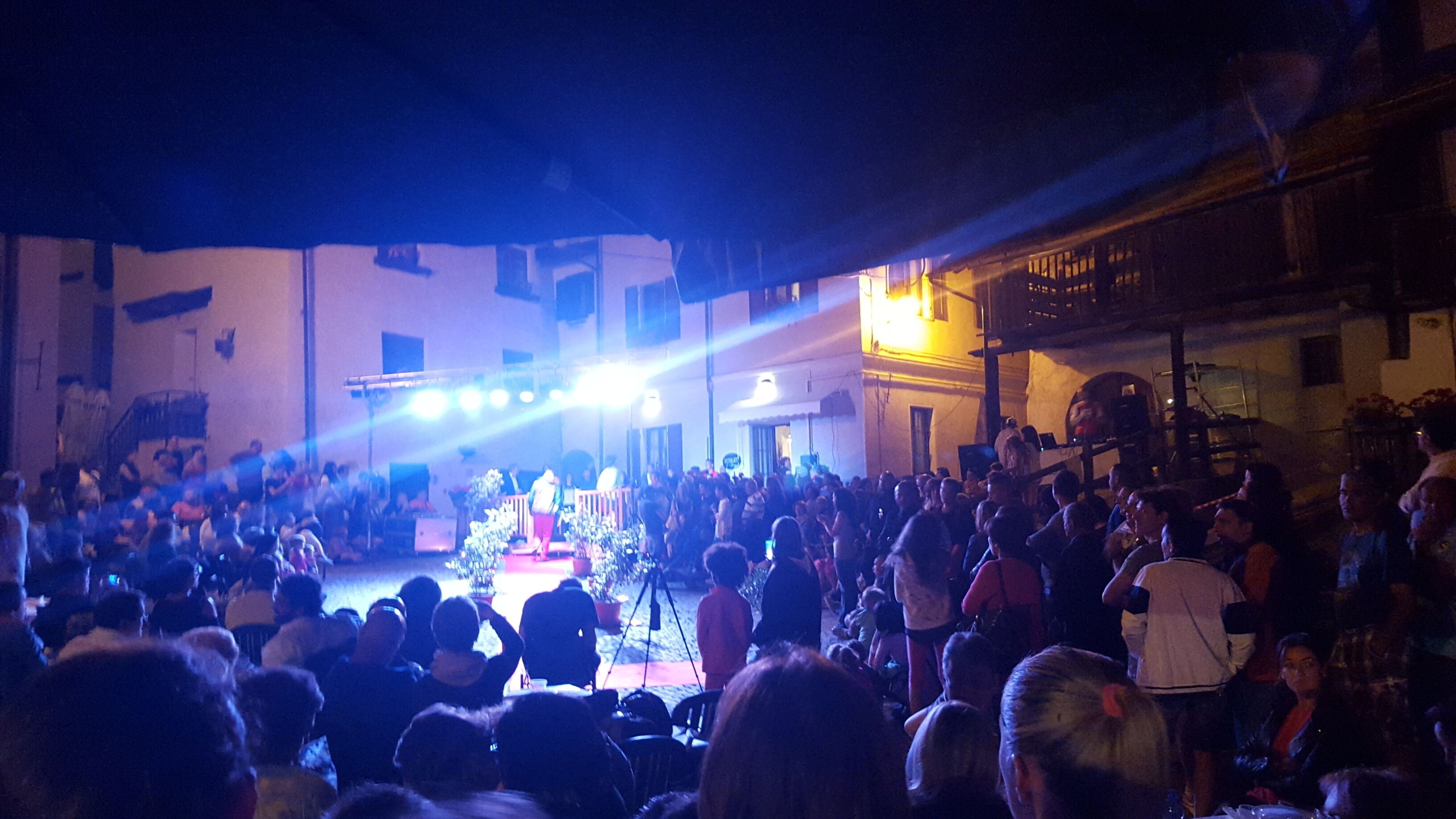 A crowded outdoor event with a stage and audience.