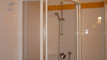 A shower enclosure with a curved door, a handheld showerhead, and a wall-mounted faucet.