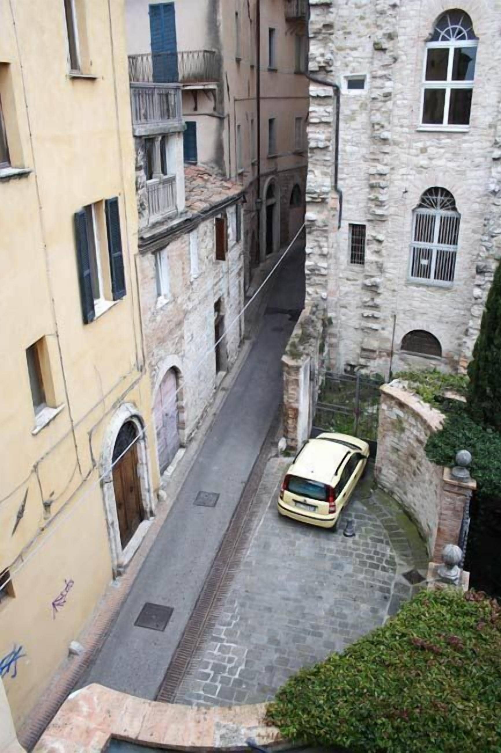 Une rue étroite bordée de bâtiments historiques, avec une voiture garée sur le côté.