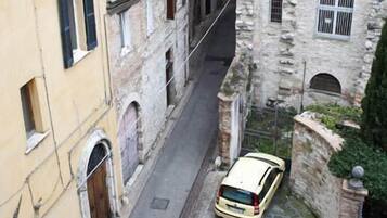 Une rue étroite bordée de bâtiments historiques, avec une voiture garée sur le côté.