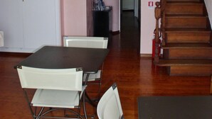 A room with a dining table, chairs, a staircase, and a door leading to another room.