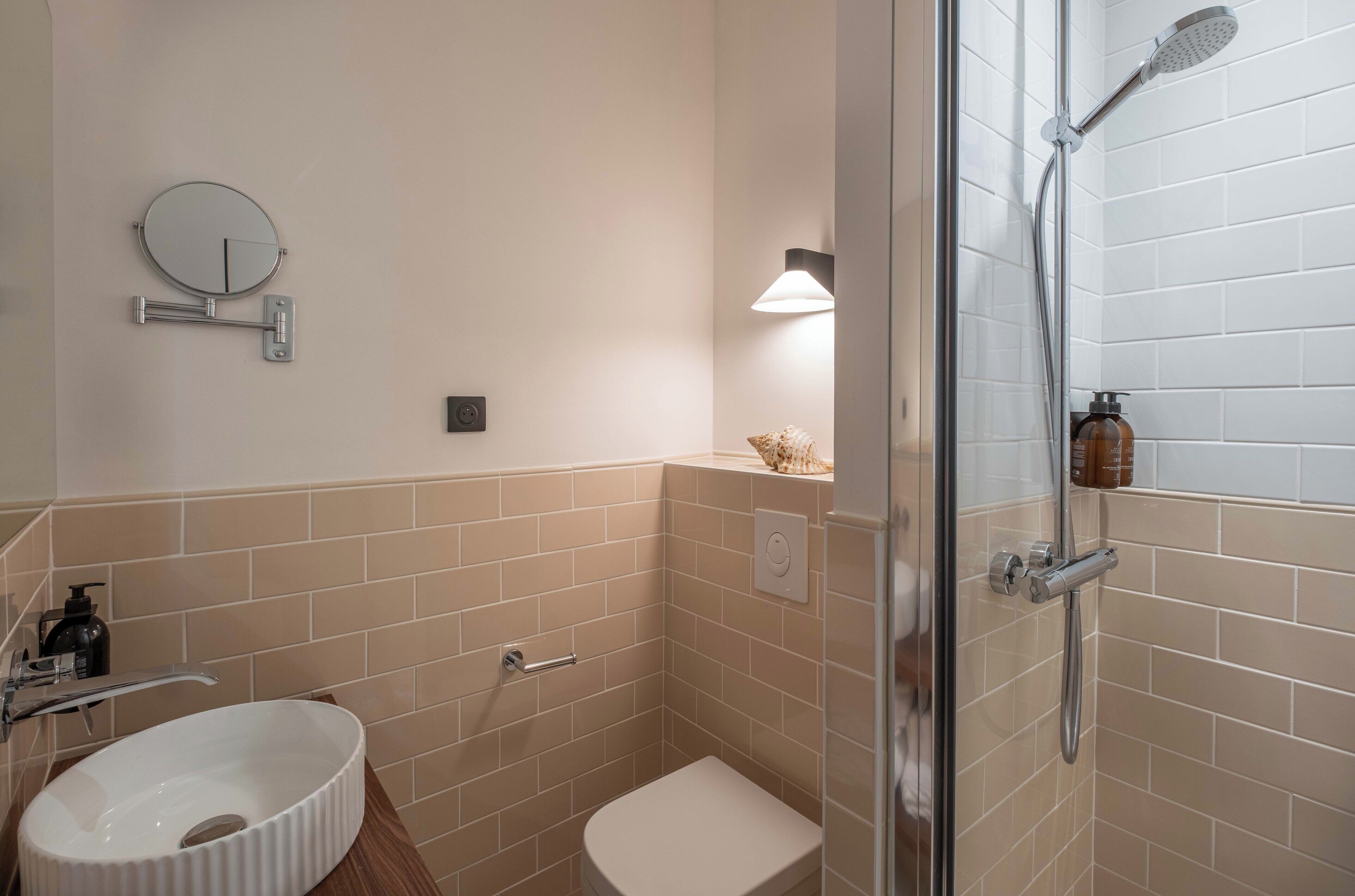 A compact bathroom with a white sink, a toilet, a glass-enclosed shower, and a wall-mounted mirror.