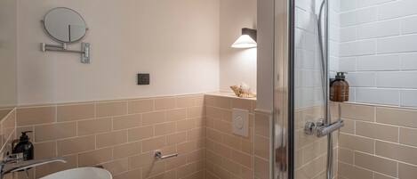 A compact bathroom with a white sink, a toilet, a glass-enclosed shower, and a wall-mounted mirror.