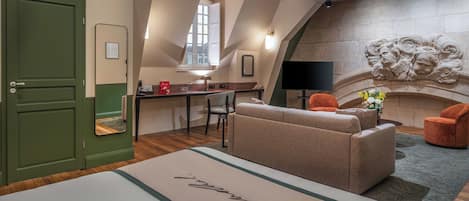Una habitación de hotel con cama, escritorio, televisión y chimenea.