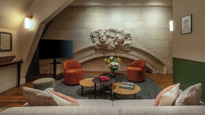 A cozy lounge area with a stone fireplace, comfortable seating, and a flat-screen TV. - Hôtel Littéraire Stendhal et Spa (Nancy)