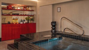 A spa area with a hot tub, a reception desk, and a wall-mounted shelf with amenities. - Hôtel Littéraire Stendhal et Spa (Nancy)